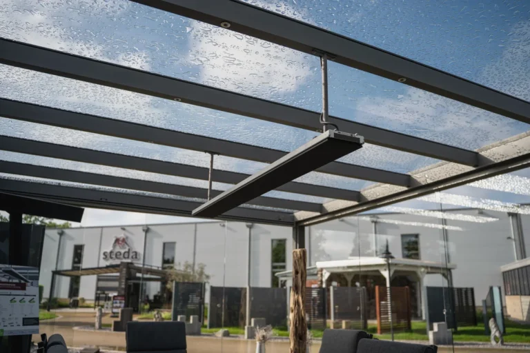 Anthrazitfarbener Infrarot-Heizstrahler unter Glas-Terrassenüberdachung mit Aluminiumrahmen bei Regen