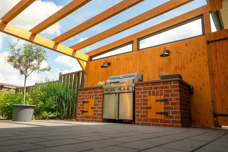 Terrassenüberdachung aus Glas mit Holzrahmen und integrierter Outdoor-Küche aus Klinker