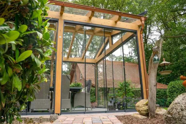 Freistehende Terrassenüberdachung aus Glas mit Holzrahmen und Glasschiebewänden im Garten